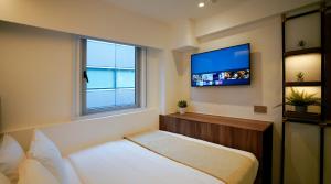 ein Schlafzimmer mit einem Bett und einem TV an der Wand in der Unterkunft ST Signature Bugis Middle, SHORT OVERNIGHT, 11 hours 8PM-7AM in Singapur