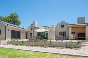 a house with a patio with a table and an umbrella at Eikenhof Estate in Brackenfell