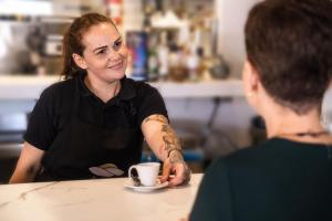 una mujer sentada en una mesa con una taza de café en Hotel Adonis Plaza, en Santa Cruz de Tenerife