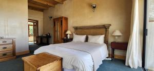 a bedroom with a large white bed with a wooden headboard at Monkey Valley Resort in Noordhoek