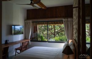 um quarto com uma cama, uma secretária e uma janela em Mùa Dalat Wellness Hotel em Da Thien