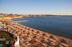 a beach with many umbrellas and the water at Sunrise Arabian Beach Resort in Sharm El Sheikh