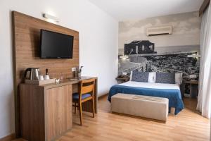 a bedroom with a bed and a desk and a tv at Hotel Adonis Plaza in Santa Cruz de Tenerife