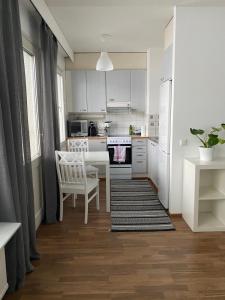 ヨエンスーにあるTilava yksiö Niinivaarallaの白いキャビネット、テーブルと椅子付きのキッチンが備わります。