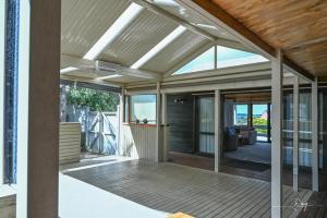 an open patio with a wooden deck with a roof at Sunny Beachview Homestay Auckland in Auckland