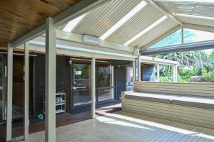 an empty screened porch with awning and glass doors at Sunny Beachview Homestay Auckland in Auckland