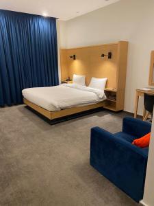 um quarto de hotel com uma cama e um sofá azul em La Maison Islamabad em Islamabad