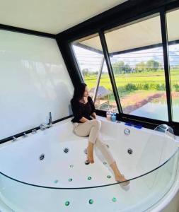 una donna seduta su una vasca in una stanza con finestre di Sean Sawat Resort 2 
