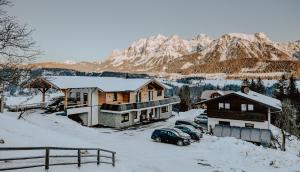 a group of buildings in the snow with mountains at Bucheggerhof in Schladming
