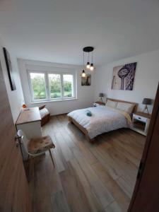 a bedroom with a bed and a desk and two windows at Le bord de Sarre in Sarreguemines