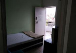 a small bedroom with a small bed and a window at Hotel Amba Amravati in Amrāvati