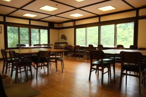 uma sala de jantar com mesas, cadeiras e janelas em Kaya Yamanoie em Yosano