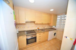 a kitchen with wooden cabinets and a sink and a dishwasher at Estoril III vista mar Orangecosta in Benicàssim