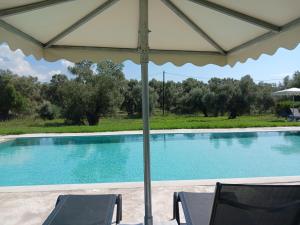 a swimming pool with two chairs and an umbrella at Rock Rooms in Lefkada +17 photos