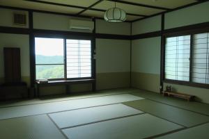an empty room with two large windows in a building at Kaya Yamanoie in Yosano