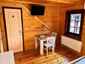 Zimmer mit einem Tisch und einem TV in einer Hütte in der Unterkunft Ubytovanie v Superior izbách v podkroví Koliba Pacho in Prievidza