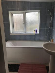 a bathroom with a tub and a window and a sink at Lovely 1 bed flat in great location with garden in Ilford