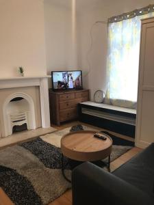 a living room with a tv and a fireplace at Lovely 1 bed flat in great location with garden in Ilford