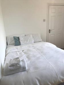 a white bed with a towel on top of it at Lovely 1 bed flat in great location with garden in Ilford