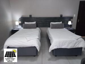 two beds in a hotel room with white sheets and pillows at SnL 12 Dwergarend in Malelane
