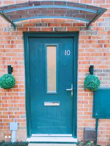 une porte bleue sur une maison en briques avec deux plantes dans l'établissement Dream Haute Homes, à Nottingham
