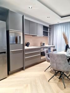 una cocina con electrodomésticos de acero inoxidable, mesa y sillas en Bridgewater One by Smart City Stays, en Ciudad del Cabo