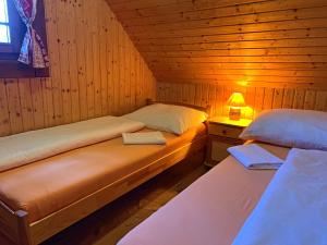 2 Betten in einem Holzzimmer mit einer Lampe in der Unterkunft Ubytovanie Koliba Pacho - Zrub Zuzka in Prievidza