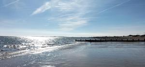 una playa con un muelle y el sol reflejándose en el agua en Guest suite 50m from the beach en Bognor Regis