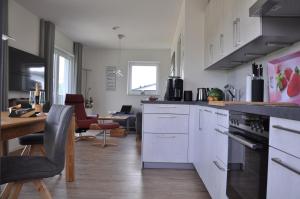 uma cozinha com armários brancos e uma mesa e cadeiras em Ferienhaus Catharina em Diemelsee