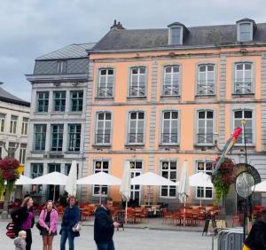 grupa ludzi idących przed dużym budynkiem w obiekcie Le Vieux Cèdre Grand Place w mieście Mons
