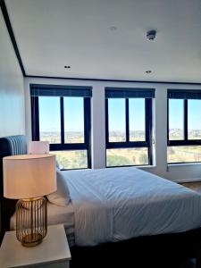sypialnia z dużym łóżkiem i oknami w obiekcie Bridgewater One by Smart City Stays w Kapsztadzie