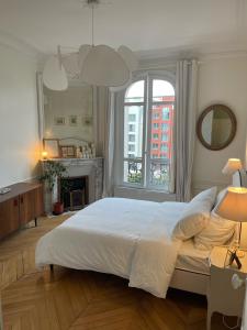 een slaapkamer met een groot wit bed en een open haard bij Grand appartement Haussmannien à 12 min de Paris - Proche Stade de France - Jeux Olympiques 2024 in Enghien-les-Bains