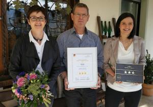 un homme et deux femmes tenant une plaque dans l'établissement Weinhaus Berg, à Bremm