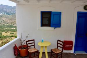 Theoreion في Tholária: طاولة صفراء وكراسي على شرفة مع أبواب زرقاء