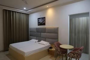 ein Schlafzimmer mit einem Bett, einem Tisch und Stühlen in der Unterkunft Radha Madhav Hotel & Banquet in Palwal