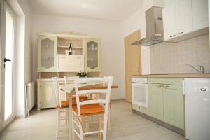 a kitchen with white cabinets and a table and chairs at Banić Apartments with pool in Biograd na Moru