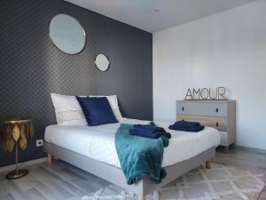 een slaapkamer met een bed met blauwe kussens en een spiegel bij La Marée - Appt à 50m de la plage in Bray-Dunes +1 foto