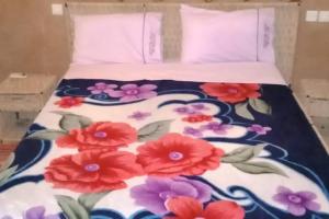 a bed with a floral bedspread with red flowers on it at Bivouac Liguera chez Ahmed in Mhamid