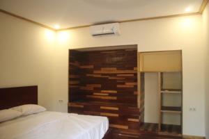 a bedroom with a bed and a wooden wall at Gili Tempoe in Gili Trawangan