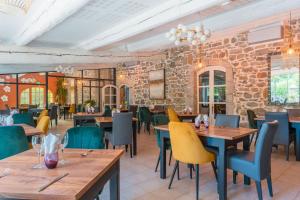 a restaurant with wooden tables and chairs and a brick wall at Logis Hôtel Restaurant Le Pradinas in Anduze
