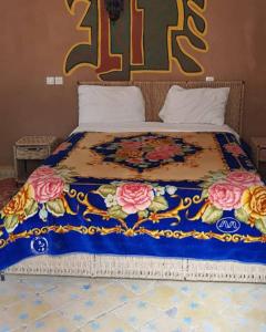a bed with a blue blanket with flowers on it at Bivouac Liguera chez Ahmed in Mhamid