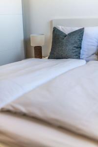 a white bed with a pillow and a lamp at Hangar 19 Superior Apartment mit Seeblick H5W2 in Schwerin