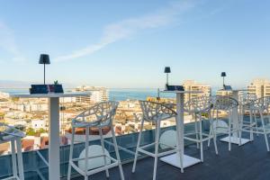 een balkon met tafels en stoelen en uitzicht op de stad bij AluaSoul Costa Malaga - Adults recommended in Torremolinos