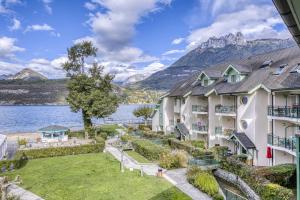 an exterior view of a resort with a lake and mountains at La Terrasse du Lac in Duingt