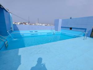 a shadow of a person standing next to a swimming pool at Hotel City Heart Shirdi in Shirdi