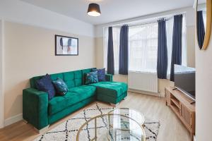 a living room with a green couch and a tv at Elfleda Stay - Modern 5 bedroom house with parking in Cambridge