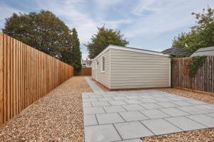 a wooden fence and a small garage in a yard at Elfleda Stay - Modern 5 bedroom house with parking in Cambridge