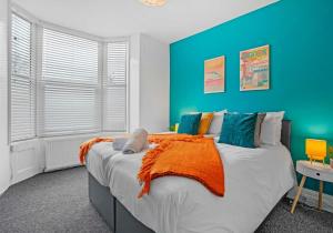 1 dormitorio azul con 1 cama grande con manta naranja en Dorset Green By My Getaways, en Brighton & Hove