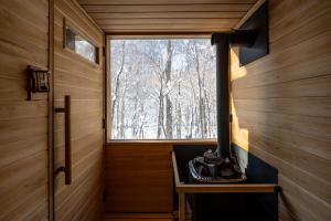 une fenêtre dans une pièce en bois avec un poêle dans l'établissement Moving Inn Tokachi Kitanomori, à Taiki