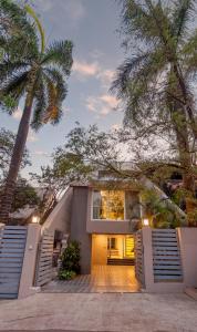 een huis met palmbomen ervoor bij Villa Belle Vue- 4BHK Private Pool & Party Hall By StayMonkey in Lonavala